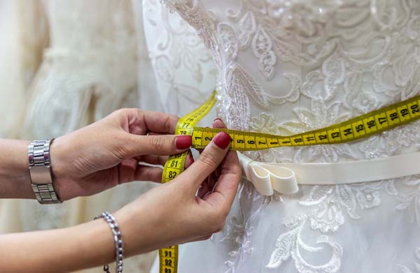 Female hands with measuring tape and wedding dress